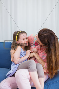 Mother and daughter laughing on couch