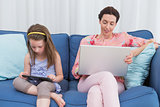 Mother and daughter using tablet and laptop