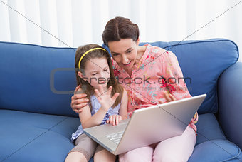 Mother and daughter video chatting with laptop
