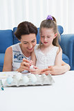 Mother and daughter painting easter eggs