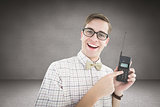 Composite image of geeky hipster holding a retro cellphone