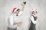 Composite image of geeky hipster running away from a man with mistletoe