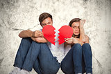 Composite image of young couple holding broken heart