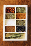set of different spices (pepper, salt, turmeric, bay leaves, chili, herbs) in a wooden box