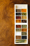 set of different spices (pepper, salt, turmeric, bay leaves, chili, herbs) in a wooden box