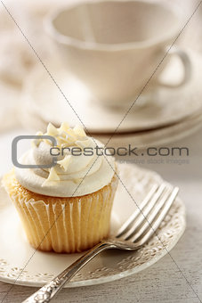 Closeup of vanilla cupcake with tea cup