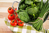 Fresh spinach leaves with tomatoes and strainer