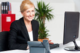 Cheerful aged woman working at the desk
