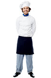 Young chef standing with hands behind