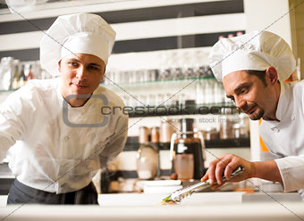 Chef watching his assistant arranging dish