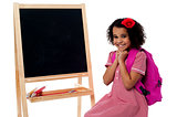 Pretty girl sitting near blank chalk board