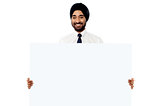 Smiling young man holding white sign board