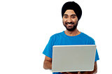 Smiling young guy using his laptop