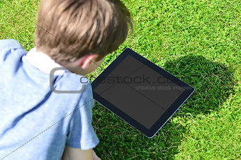 Young boy using digital tablet outdoors