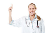 Smiling female doctor pointing upwards