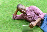 Handsome man lying on the lawn with tablet