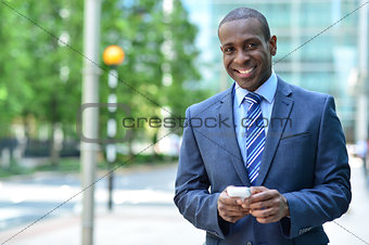 Smiling businessman holding smartphone