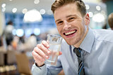 Smiling young man drinking water in restaurant