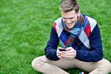 Cheerful young relaxed guy using mobile phone