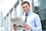 Cheerful entrepreneur reading newspaper