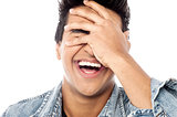 Laughing young man with hand on his face