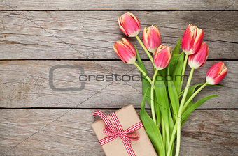 Colorful tulips and gift box on wooden table