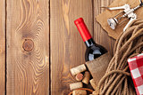 Red wine bottle, corks and corkscrew over wooden table backgroun