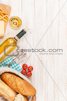 White wine, cheese and bread on white wooden table background