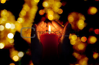 two hands illuminated by  a candle in the darkness