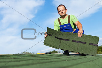 Man installing bitumen roof shingles