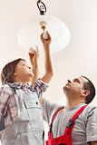 Father and son changing lightbulb in a ceiling lamp