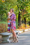 Happy mother and baby girl hugging in city park