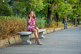 Young woman talking mobile phone in city park