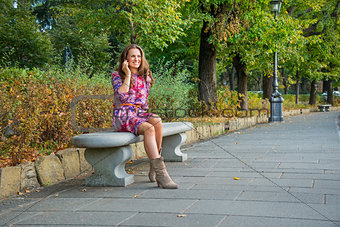 Young woman talking mobile phone in city park