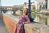 Relaxed young woman on embankment near ponte vecchio in florence
