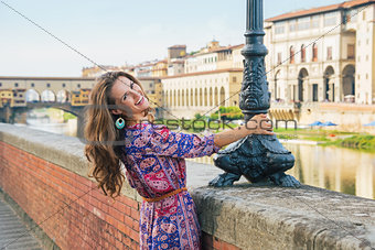 Happy young woman on embankment near ponte vecchio in florence, 