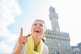 Happy young woman pointing in front of palazzo vecchio in floren