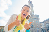 Happy young woman showing thumbs up in front of palazzo vecchio 