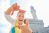 Happy young woman framing with hands in front of palazzo vecchio