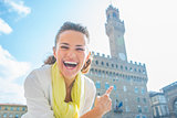 Happy young woman pointing on palazzo vecchio in florence, italy