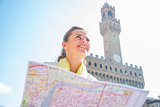 Happy young woman with map in front of palazzo vecchio in floren