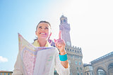 Happy young woman with map pointing in front of palazzo vecchio 
