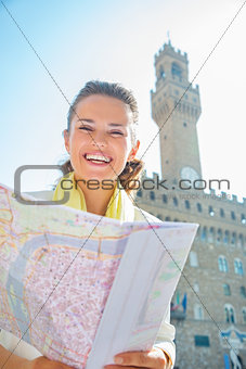 Happy young woman with map in front of palazzo vecchio in floren