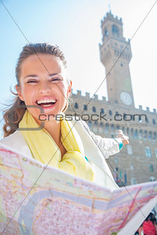 Happy young woman pointing with map pointing on palazzo vecchio 