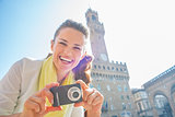 Happy young woman with photo camera in front of palazzo vecchio 