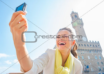 Happy young woman making selfie in front of palazzo vecchio in f