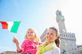 Happy mother and baby girl with flag in front of palazzo vecchio