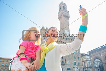 Happy mother and baby girl making selfie in front of palazzo vec