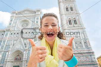 Happy young woman showing thumbs up in front of duomo in florenc
