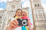Happy mother and baby girl taking photo in front of duomo in flo